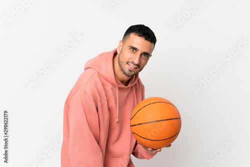 Young man over isolated white background with ball of basketball © luismolinero