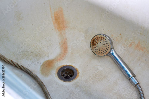 Dirty, rusty bathtub, shower in the bathroom. Unsanitary, old plumbing.