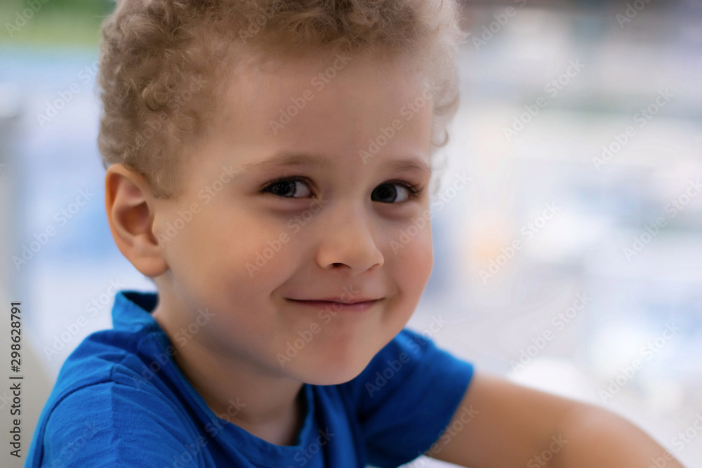 Portrait of a little curly boy. The boy is looking at the camera and smiling Portrait of a little curly boy. The boy is looking at the camera and smiling