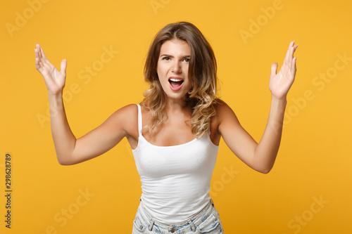 Irritated young woman in light casual clothes posing isolated on yellow orange background, studio portrait. People sincere emotions lifestyle concept. Mock up copy space. Screaming, spreading hands.
