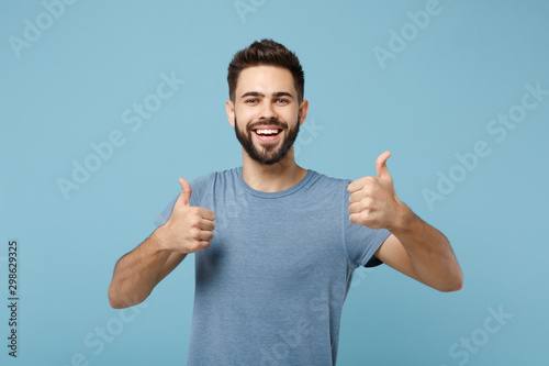 Young joyful funny smiling handsome man in casual clothes posing isolated on blue wall background, studio portrait. People sincere emotions lifestyle concept. Mock up copy space. Showing thumbs up.
