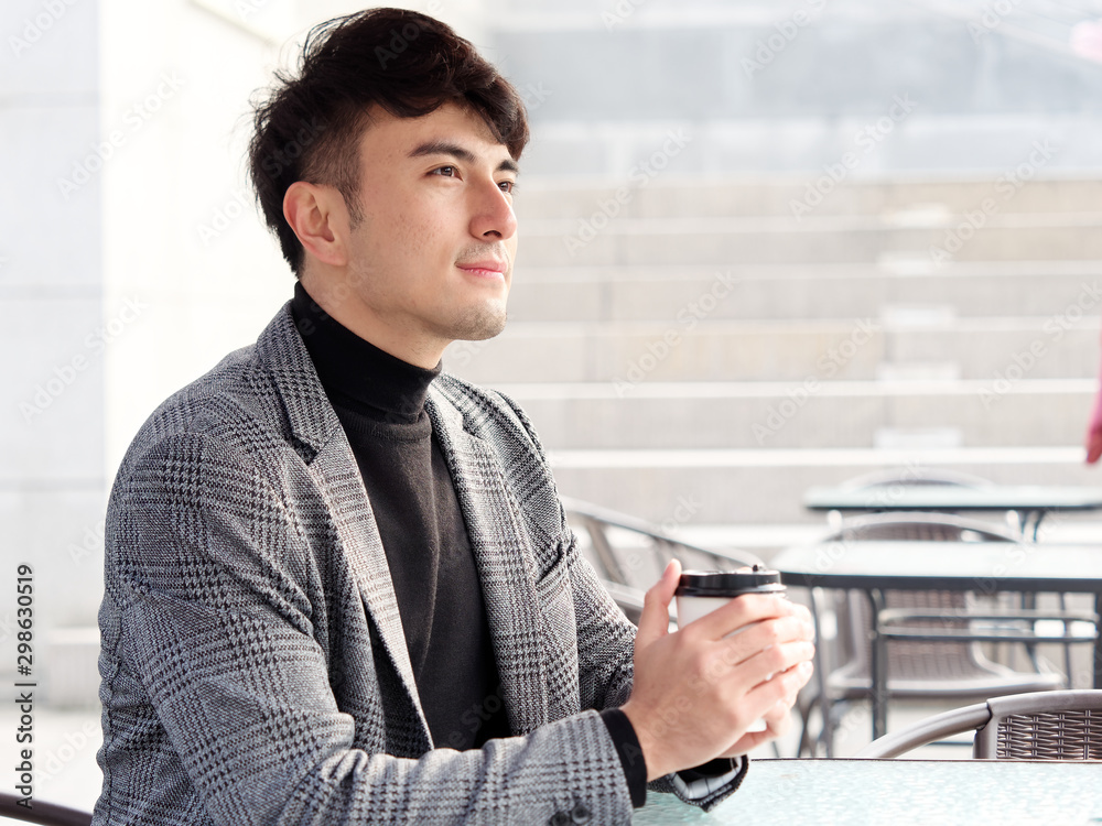 Portrait of smiling business man looking away while holding coffee cup. Handsome young man sitting and having a rest in outdoor cafe. business man lifestyle concept. Portrait of smiling business man looking away while holding coffee cup. Handsome young man sitting and having a rest in outdoor cafe. business man lifestyle concept.