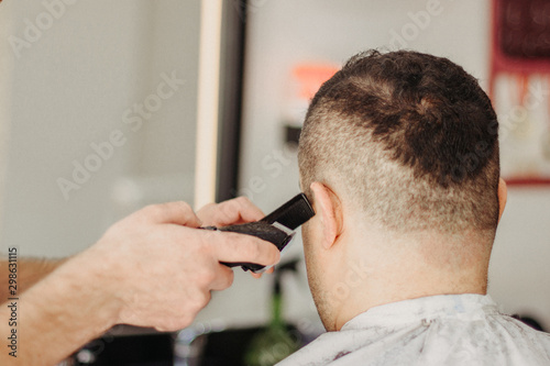 Barber making stylish haircut with professional machine in barber shop. Hair cut for turkish man