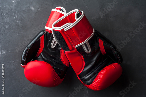 Red boxing gloves hang on the gray wall © pavel_shishkin