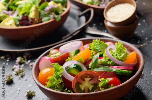 Vegetable salad of lettuce, cherry tomatoes, radish, cucumber, onion and basil on slate stone tray