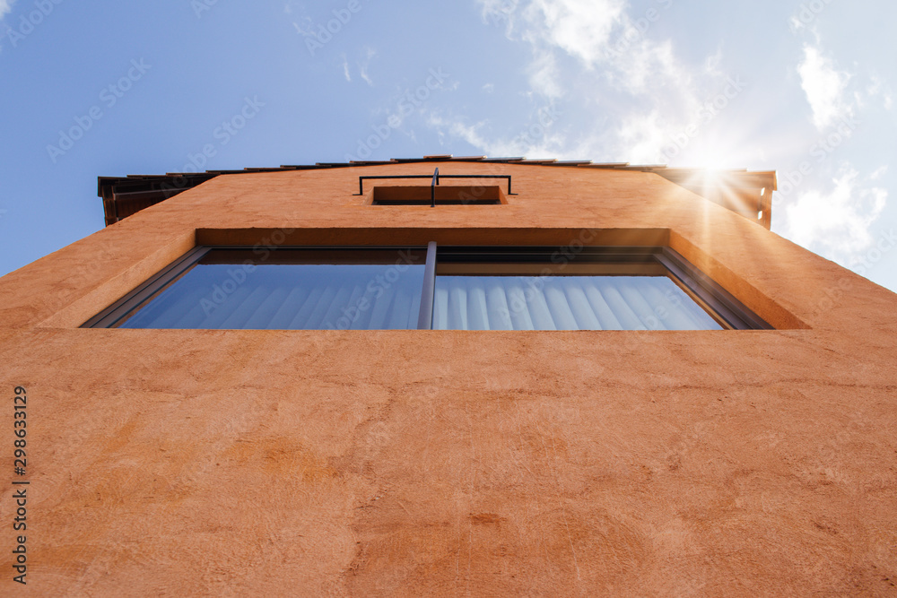 Uprisen angle view of resident with orange clay wall and blue sky in background. Uprisen angle view of resident with orange clay wall and blue sky in background.