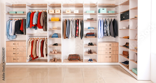Big wardrobe with clothes in dressing room