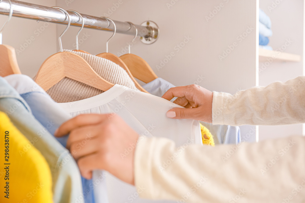 Naklejka premium Woman choosing clothes from wardrobe in dressing room, closeup