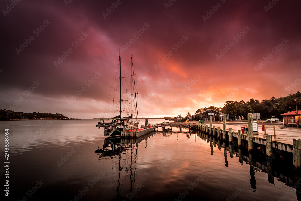 Sailing boat with idyllic sunset in Strahan, Tasmania one of the most remote places in Australia at the end of the world with beautiful colors in the sky, starting point for a trip on the Gordon River