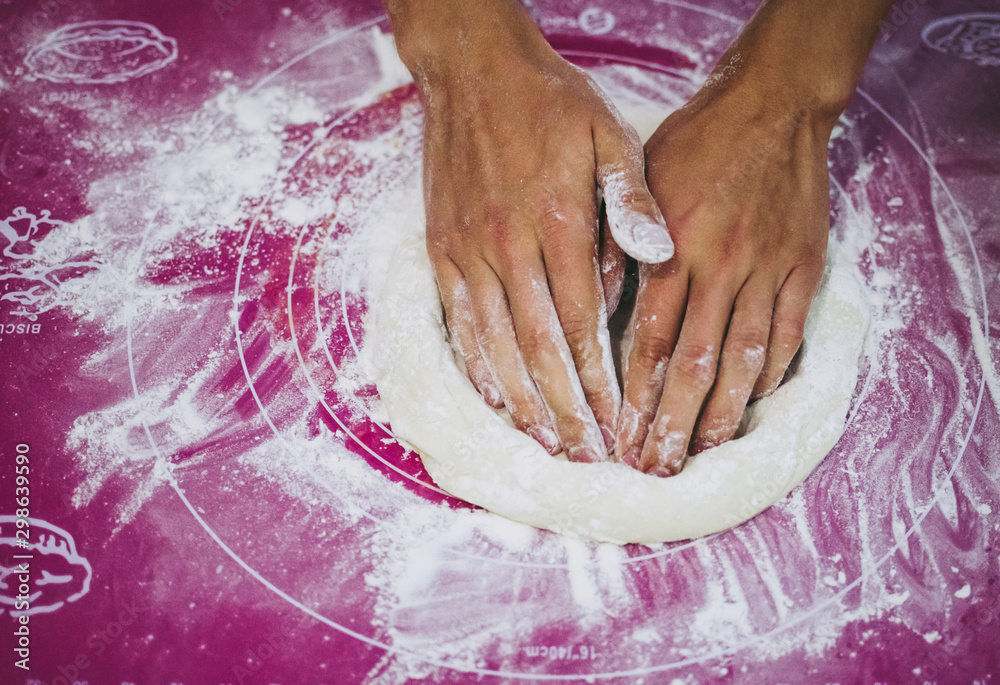 Pizzaiolo kneading pizza dough with his hands, purple background. Homemade pizza preparation process