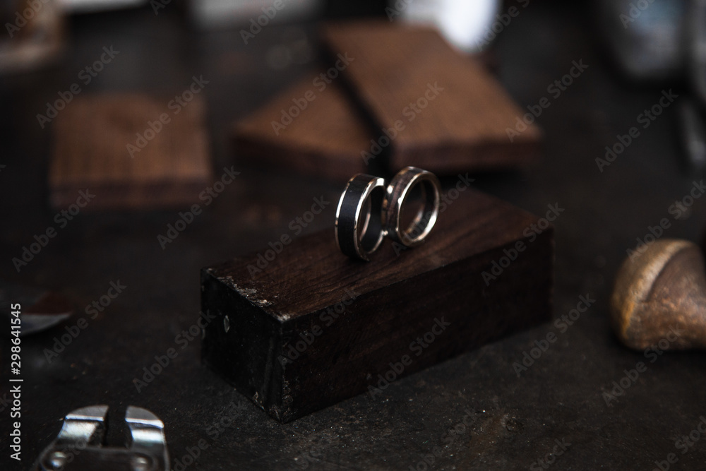 Wooden rings and Golden on the table at the jeweler. Dark table with decorations. Jewelry workshop. Wooden rings and Golden on the table at the jeweler. Dark table with decorations. Jewelry workshop.
