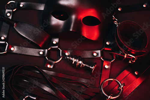 Female set of sex toys from a sex shop for BDSM sex. Mask, leather belt, choker, handcuffs, whip and anal plug