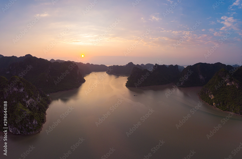 Aerial view of Ha Long from Bay Cat Ba island, unique limestone rock islands and karst formation peaks in the sea, famous tourism destination in Vietnam. Sunset scenic sky.