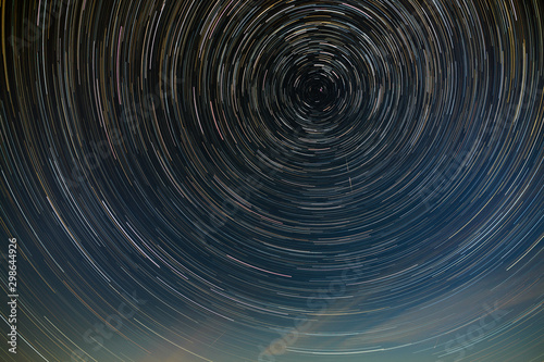 Star trail in the night sky with clouds.