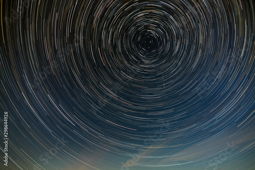 Star trail in the night sky with clouds.