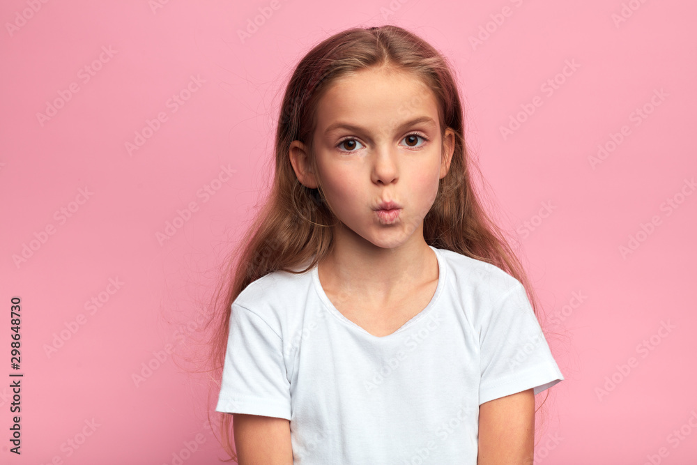 closeup portrait of serious little kid in white t-shirt with pursed lips and large eyes. kid staring at the camera . close up portrait, isolated pink background. closeup portrait of serious little kid in white t-shirt with pursed lips and large eyes. kid staring at the camera . close up portrait, isolated pink background.