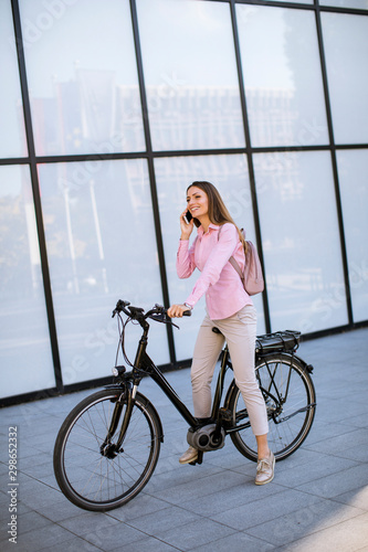 Young woman with ebicycle using on mobile phone photo