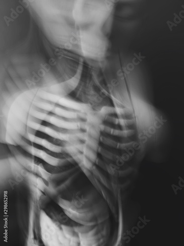 Abstract disease and disorder concept. Human body with bones and internal organs. Long exposure creative vertical black and white background. © bulgn