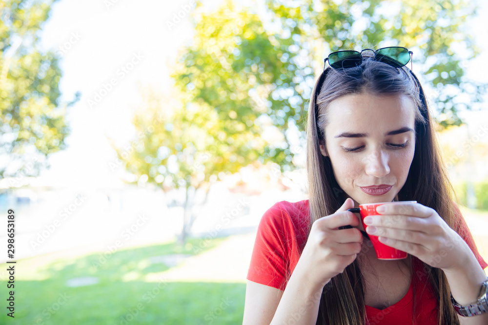 Young woman drinking coffee in the park Young woman drinking coffee in the park