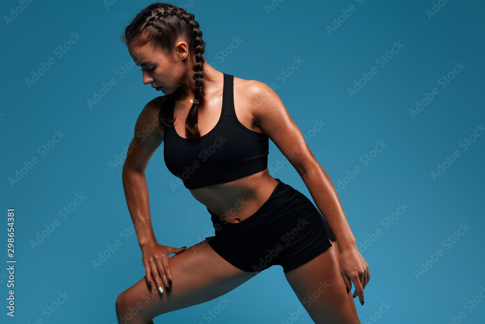 Obraz premium Young awesome slim beautiful athlete doing lunge, isolated in the blue studio. close up photo. studio shot.motivation, health and body care. lifestyle, free time, spare time