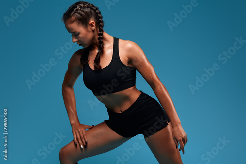 Young awesome slim beautiful athlete doing lunge, isolated in the blue studio. close up photo. studio shot.motivation, health and body care. lifestyle, free time, spare time © the faces