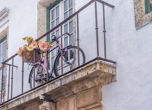 Old bicycle with flowers on a historic balcony with white walls in Obidos Portugal photo