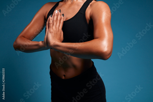 Close up of muscular strong tnned sweaty woman practising yoga, meditating. close up side view cropped photo. isolated blue background, studio shot. lifestyle, free time, spare time, wellness