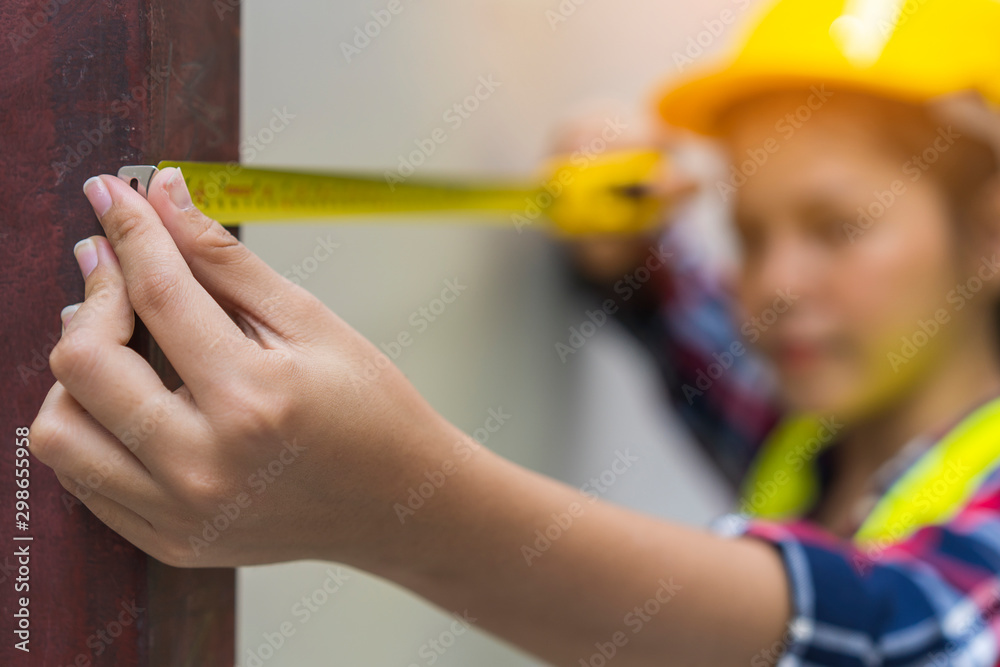 Close up hands of Construction Worker or Builder hold or using a measuring tape for home improvement or renovation. Construction, engineering, repair, building and home concept