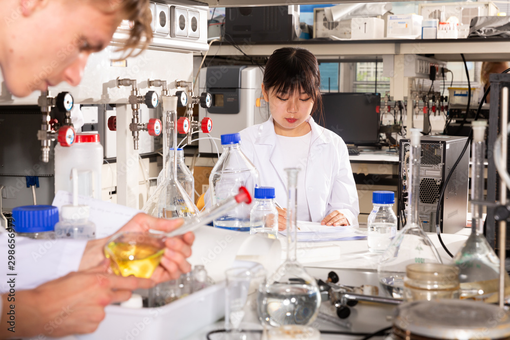 Fototapeta premium Chinese girl student recording results of experiments