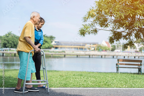 dramatic moments of young Asian carer assisting elderly or disabled using assistive walking devices, and always showcase inclusivity and acceptance when possible while spending time together on park