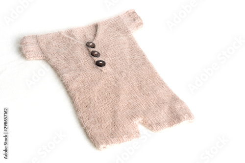 Baby clothes for newborn in brown, beige colors on white wool background. Set of baby clothes. Body for newborn.