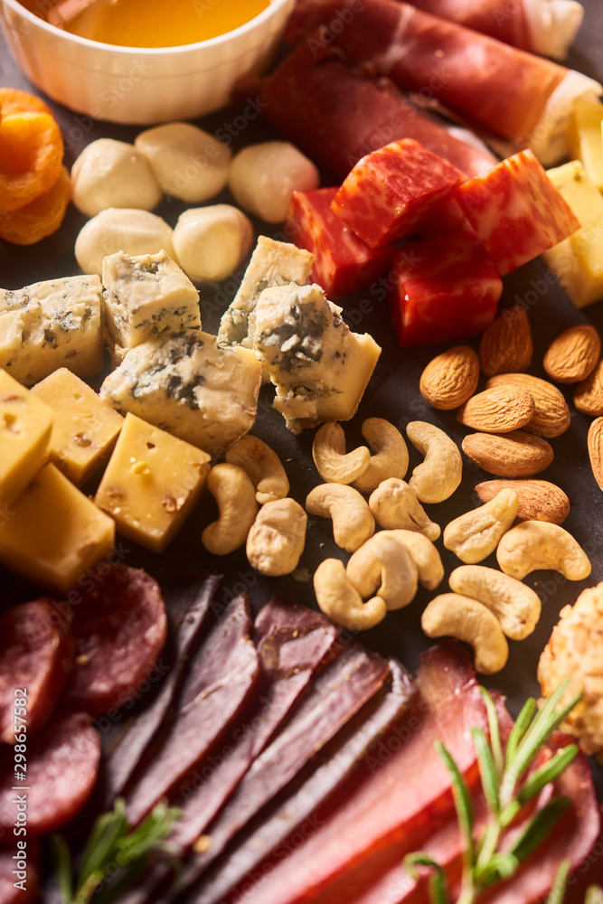different kinds of cheese, charcuterie assortment, honey, crackers, grapes, nuts and berries close up different kinds of cheese, charcuterie assortment, honey, crackers, grapes, nuts and berries close up