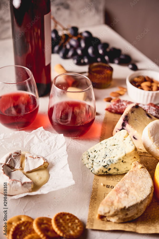 Red wine with different kinds of cheese, charcuterie assortment, crackers, grapes, nuts Red wine with different kinds of cheese, charcuterie assortment, crackers, grapes, nuts