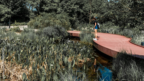 Teen in shorts and sneakers standing on red wooden walkeway photo