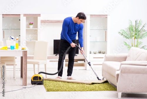 Young man vacuum cleaning his apartment