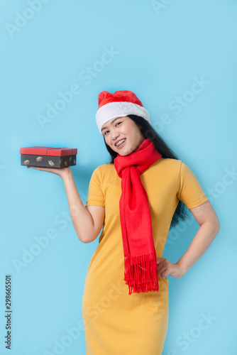 Asian woman in yellow dress wearing red scarf and Santa hat, holidays concept. © nuiiko
