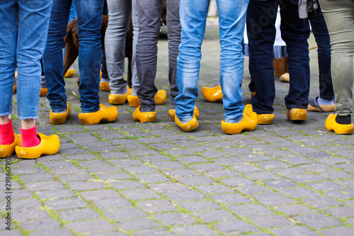 Obraz na plátně Close up of blue jeans legs of group of people wearing traditional wooden clogs