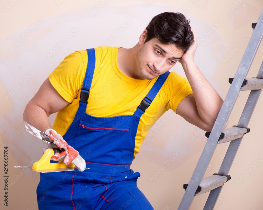 Young contractor employee applying plaster on wall Young contractor employee applying plaster on wall