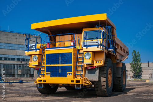 heavy yellow quarry dump truck at repair station at sunny cloudless day