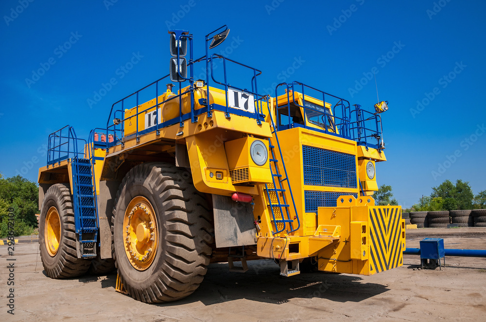 heavy yellow quarry dump truck at repair station at sunny cloudless day heavy yellow quarry dump truck at repair station at sunny cloudless day