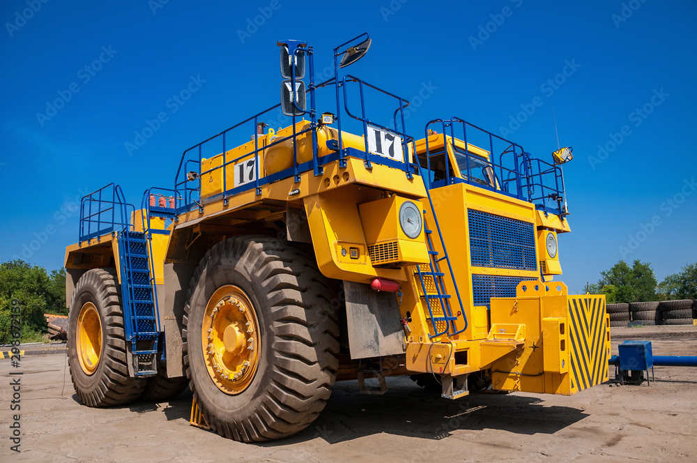 Heavy yellow quarry tractor at repair station at sunny cloudless day