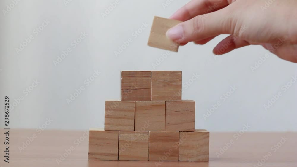 Hand putting wood cube on top of wood block stacking as step stair.business growth to success. Hand putting wood cube on top of wood block stacking as step stair.business growth to success.