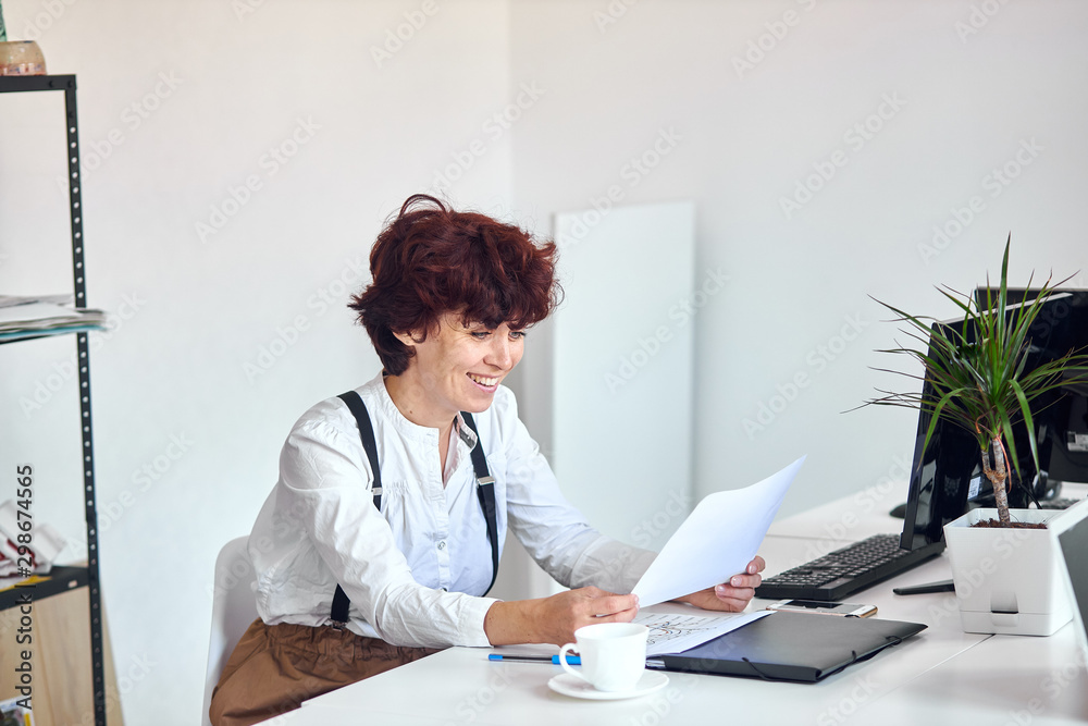 Young attractiwoman wearing white shirt sit holding papers and smile Young attractiwoman wearing white shirt sit holding papers and smile
