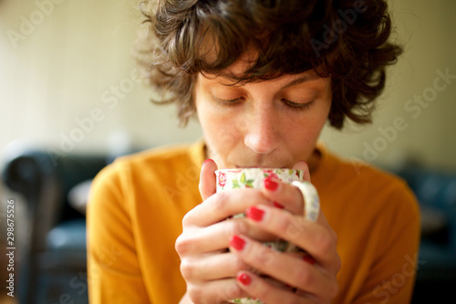 Close up woman sitting at home drinking cup of tea