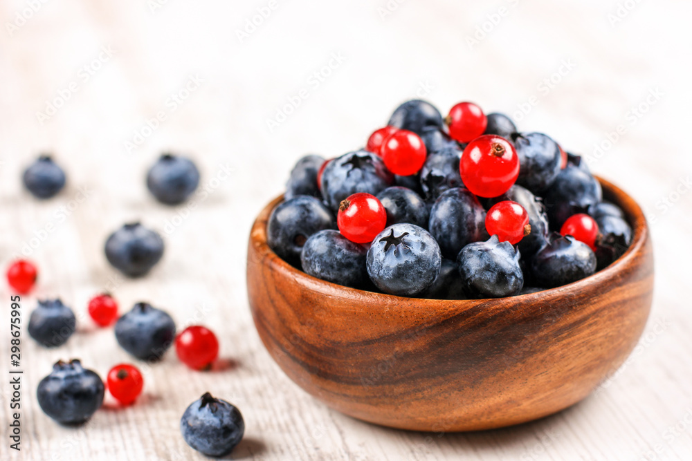 Fresh blueberries and red currants with mint leaves in a wooden bowl on burlap. Diet food, vegan berries Fresh blueberries and red currants with mint leaves in a wooden bowl on burlap. Diet food, vegan berries