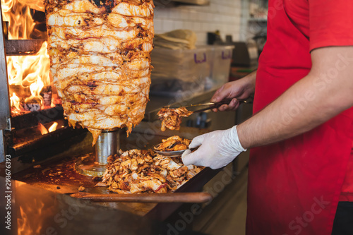 Chef preparing and making Traditional Turkish Doner Kebab meat. Shawarma or gyros. Turkish, greek or middle eastern arab style chicken doner kebab food on isolated white. photo