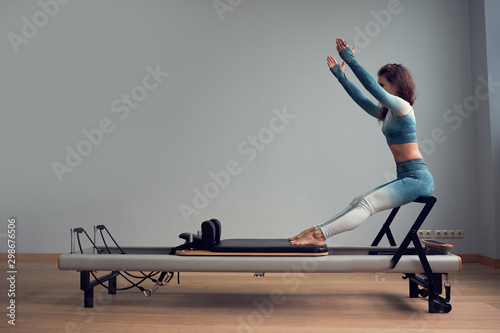 leotard workout pilates training. athletic pilates reformer exercises. pilates machine equipment. young asian woman pilates stretching sport in reformer bed instructor girl in a studio