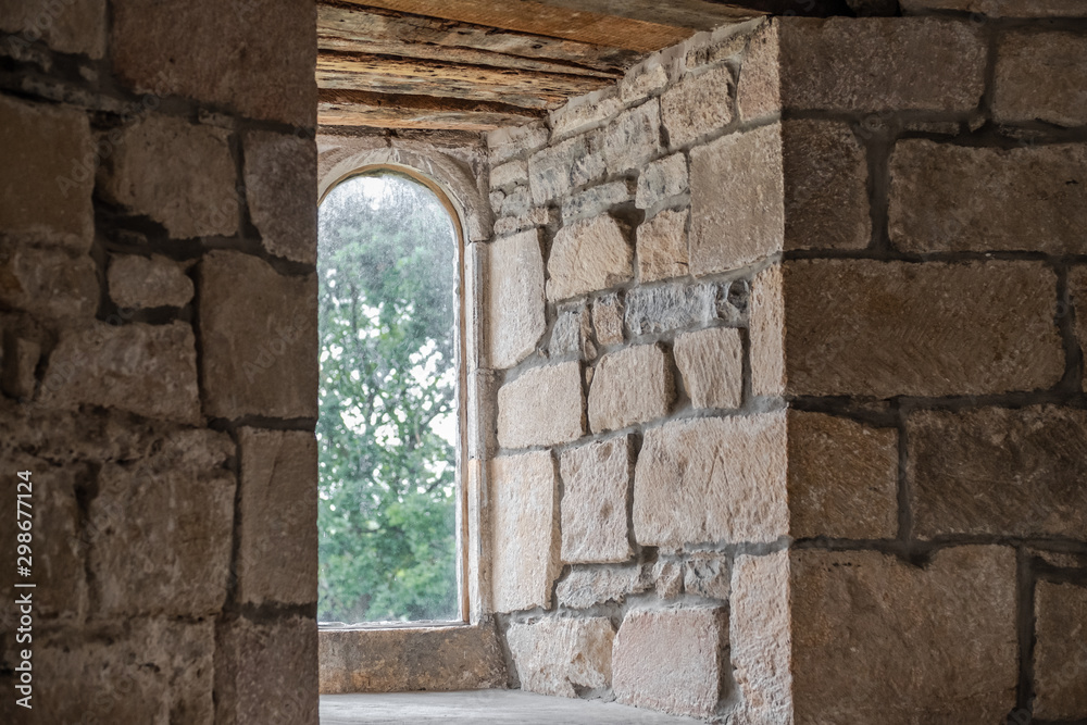 Detailed view of the interior, looking out of a medieval building. The restored stonework and arched windows are evident in this popular attraction.