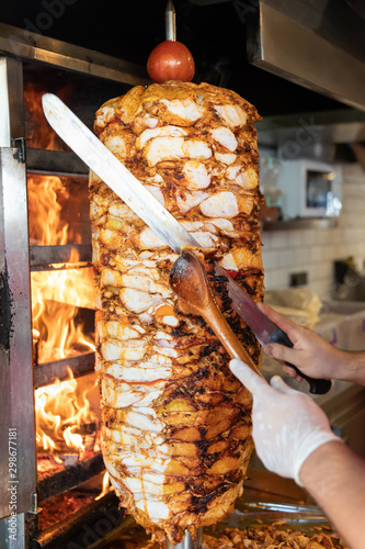 Chef cutting with doner knife Traditional Turkish Doner Kebab meat. Shawarma or gyros. Turkish, greek or middle eastern arab style chicken doner kebab food on isolated white.
