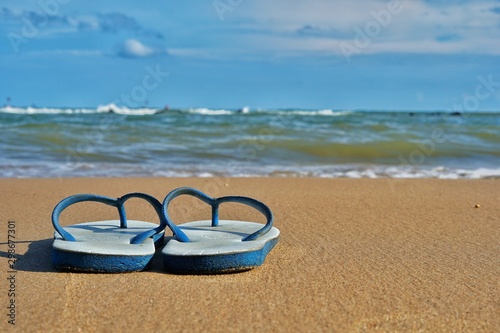 Sandals on the beach, sea and sky as the background.